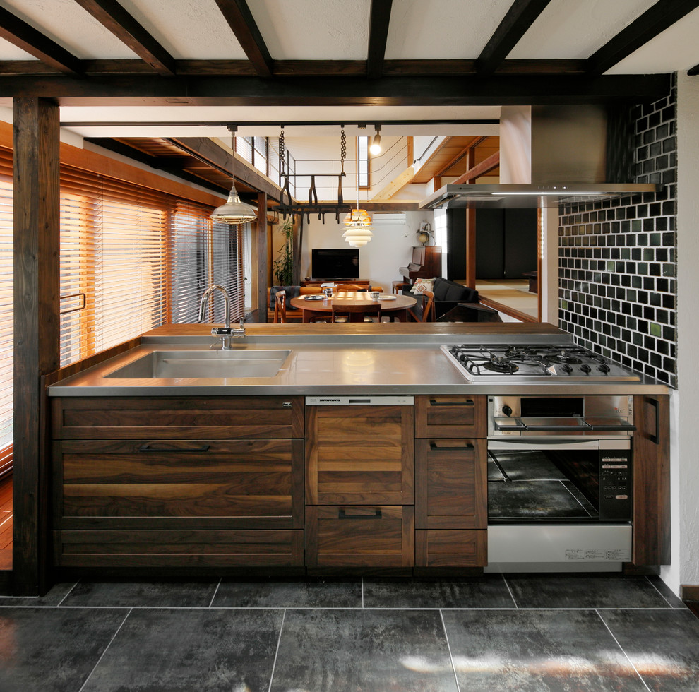 Modelo de cocina de estilo zen abierta con fregadero de un seno, armarios con paneles empotrados, puertas de armario de madera oscura, encimera de acero inoxidable, península y suelo gris