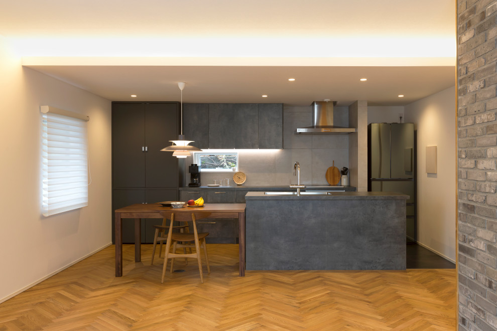 Foto på ett funkis grå kök, med en undermonterad diskho, luckor med profilerade fronter, grå skåp, grått stänkskydd, rostfria vitvaror, mellanmörkt trägolv, en köksö och brunt golv