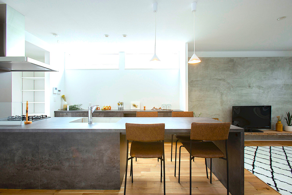 Inspiration för moderna linjära grått kök med öppen planlösning, med en undermonterad diskho, luckor med profilerade fronter, grå skåp, rostfria vitvaror, mellanmörkt trägolv, en halv köksö och brunt golv