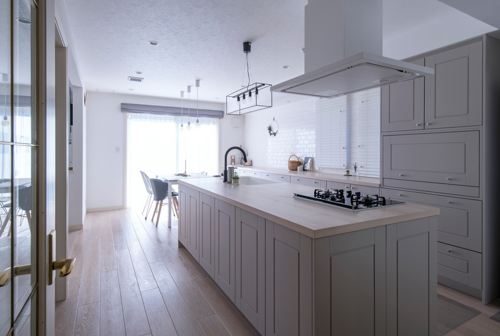Immagine di una cucina moderna con lavello sottopiano, ante a filo, ante grigie, elettrodomestici bianchi, parquet chiaro, pavimento beige e top beige