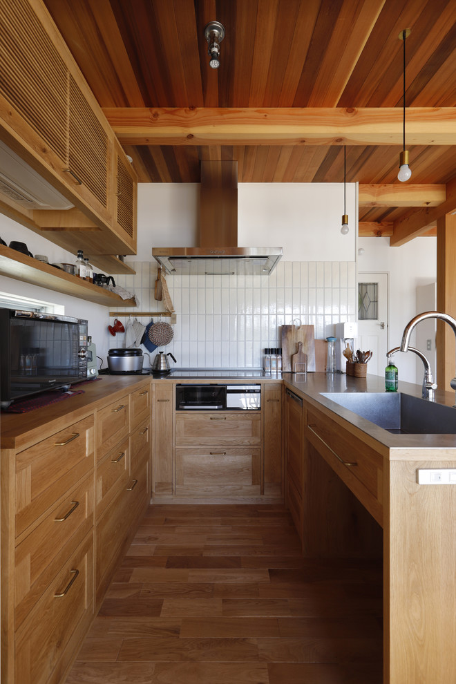 Example of a mountain style u-shaped medium tone wood floor, beige floor and exposed beam open concept kitchen design in Other with an integrated sink, recessed-panel cabinets, medium tone wood cabinets and stainless steel countertops