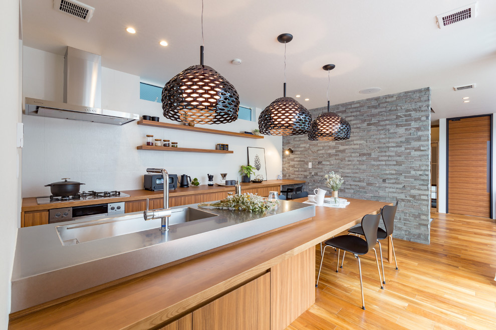 Exempel på ett modernt grå grått kök, med en integrerad diskho, släta luckor, skåp i mellenmörkt trä, bänkskiva i rostfritt stål, vitt stänkskydd, mellanmörkt trägolv, en halv köksö och brunt golv