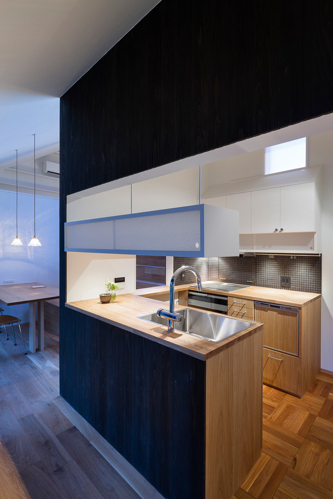 This is an example of a world-inspired u-shaped kitchen in Other with a single-bowl sink, flat-panel cabinets, medium wood cabinets, wood worktops, medium hardwood flooring, a breakfast bar and brown floors.