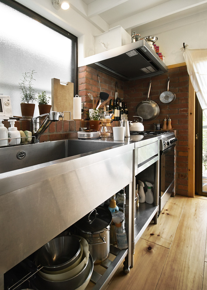 Idéer för ett litet modernt linjärt kök med öppen planlösning, med en integrerad diskho, öppna hyllor, bänkskiva i rostfritt stål, brunt stänkskydd, stänkskydd i tegel, rostfria vitvaror, mellanmörkt trägolv och beiget golv