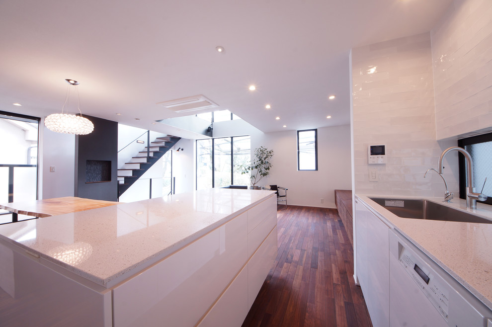 Идея дизайна: параллельная кухня-гостиная среднего размера в стиле модернизм с плоскими фасадами, белыми фасадами, столешницей терраццо и островом