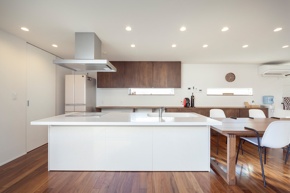 Mid-century modern single-wall brown floor and medium tone wood floor open concept kitchen photo in Other with an integrated sink, an island and white countertops