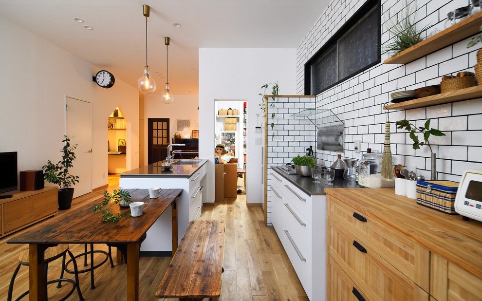 Стильный дизайн: параллельная кухня-гостиная в скандинавском стиле с одинарной мойкой, плоскими фасадами, белыми фасадами, паркетным полом среднего тона, полуостровом и коричневым полом - последний тренд