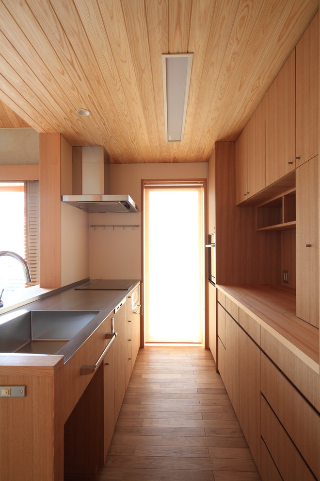 This is an example of an enclosed kitchen in Nagoya with an integrated sink, flat-panel cabinets, medium wood cabinets, stainless steel worktops, white splashback, medium hardwood flooring, beige floors, beige worktops and a wood ceiling.