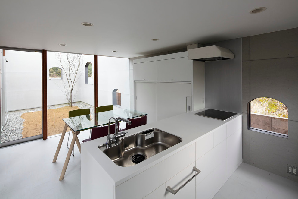 Foto di una cucina abitabile moderna con lavello sottopiano, ante in stile shaker, ante bianche, elettrodomestici in acciaio inossidabile e penisola