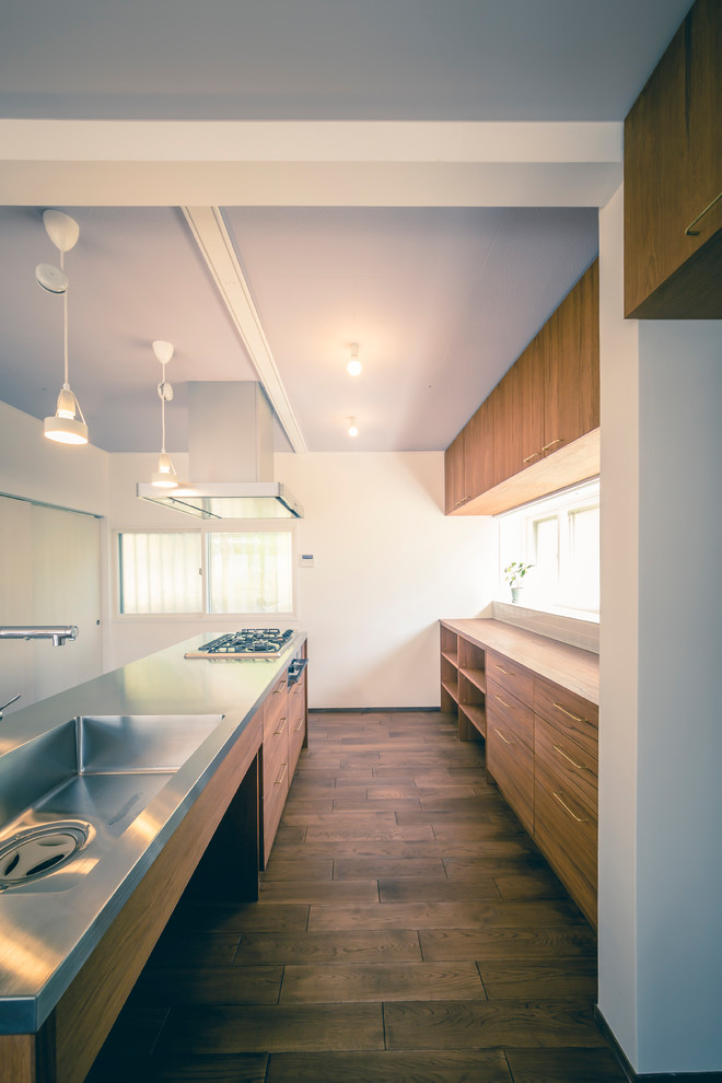 Foto på ett stort minimalistiskt brun linjärt kök med öppen planlösning, med en enkel diskho, öppna hyllor, skåp i mörkt trä, bänkskiva i rostfritt stål, vitt stänkskydd, stänkskydd i keramik, rostfria vitvaror, mörkt trägolv, en köksö och brunt golv