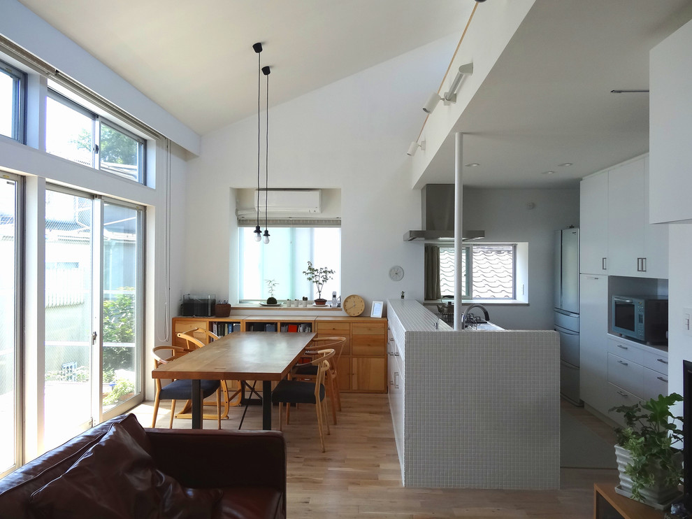 Inspiration for a medium sized modern open plan kitchen in Tokyo with medium hardwood flooring, beige floors, flat-panel cabinets, white cabinets and a breakfast bar.