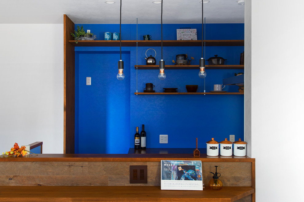 Cette photo montre une petite cuisine linéaire tendance en bois brun avec un placard sans porte, un plan de travail en bois et une crédence bleue.