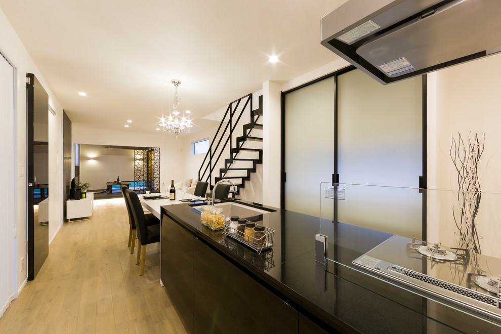 Cette photo montre une cuisine ouverte linéaire moderne avec un plan de travail en granite, un électroménager en acier inoxydable, parquet clair et un sol beige.