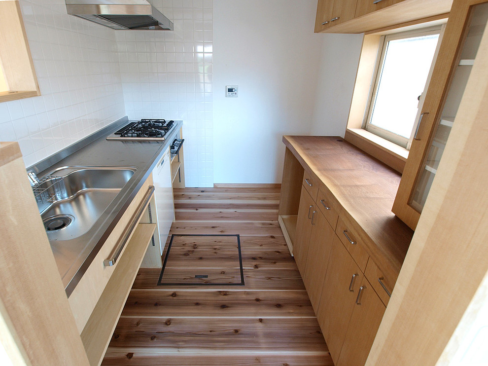 This is an example of a scandi single-wall enclosed kitchen in Other with an integrated sink, open cabinets and stainless steel worktops.