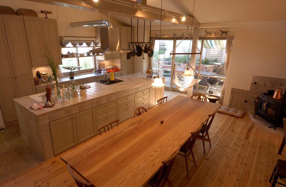 Foto på ett nordiskt linjärt kök och matrum, med en nedsänkt diskho, luckor med profilerade fronter, vita skåp, kaklad bänkskiva, rostfria vitvaror, ljust trägolv och en köksö
