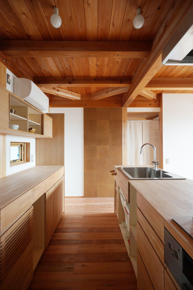 Photo of a world-inspired kitchen in Other with a single-bowl sink, flat-panel cabinets, medium wood cabinets, wood worktops, medium hardwood flooring, an island and brown floors.