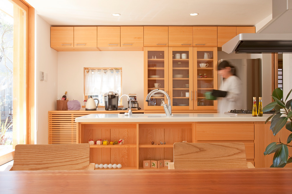На фото: параллельная кухня в восточном стиле с обеденным столом, стеклянными фасадами, светлыми деревянными фасадами, островом и белой столешницей