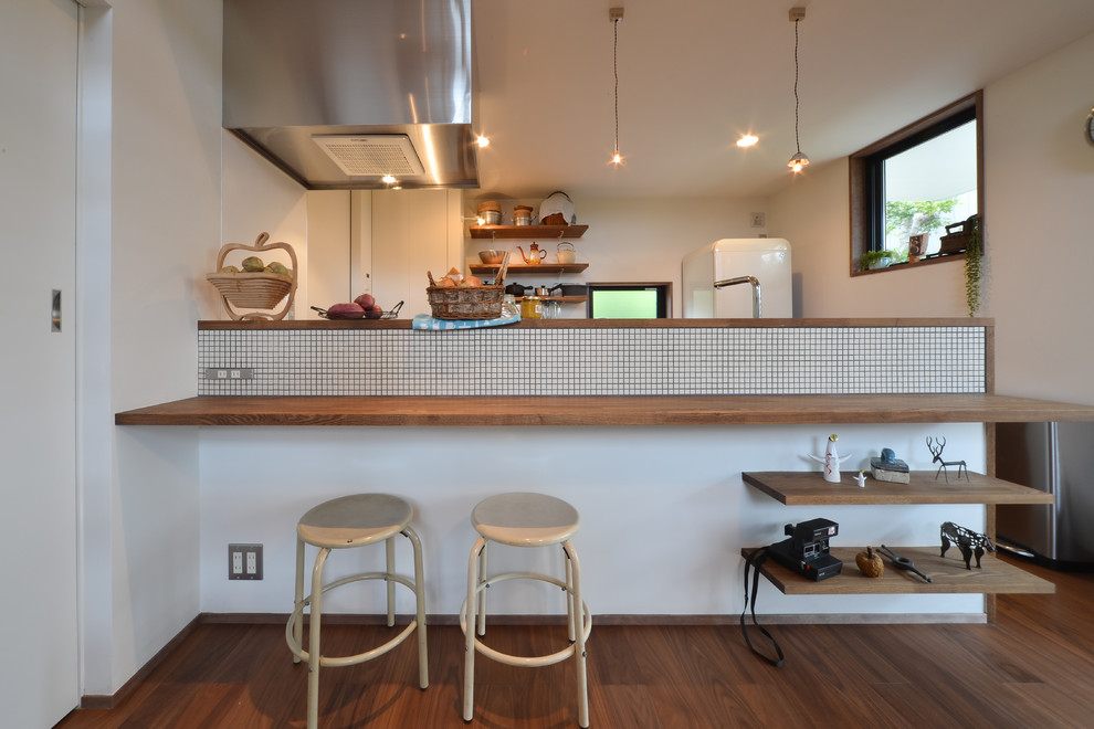 World-inspired single-wall open plan kitchen in Nagoya with a breakfast bar, medium hardwood flooring and brown floors.