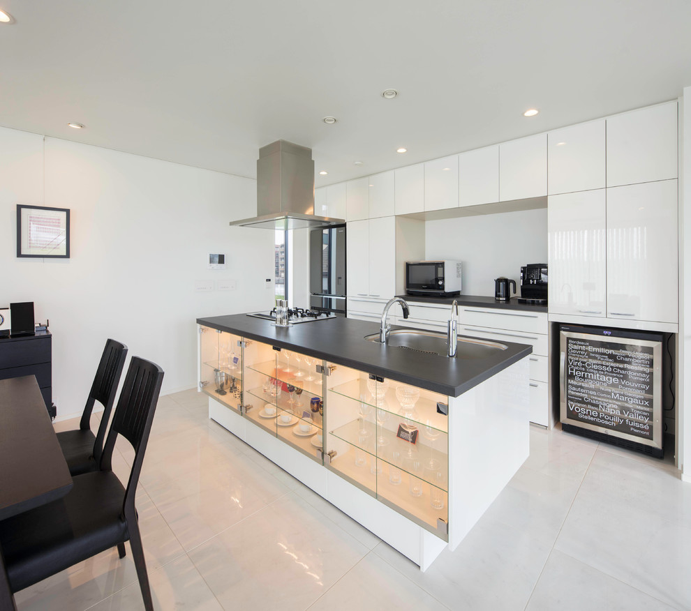 Foto på ett funkis linjärt kök med öppen planlösning, med en enkel diskho, släta luckor, vita skåp, en köksö och vitt golv