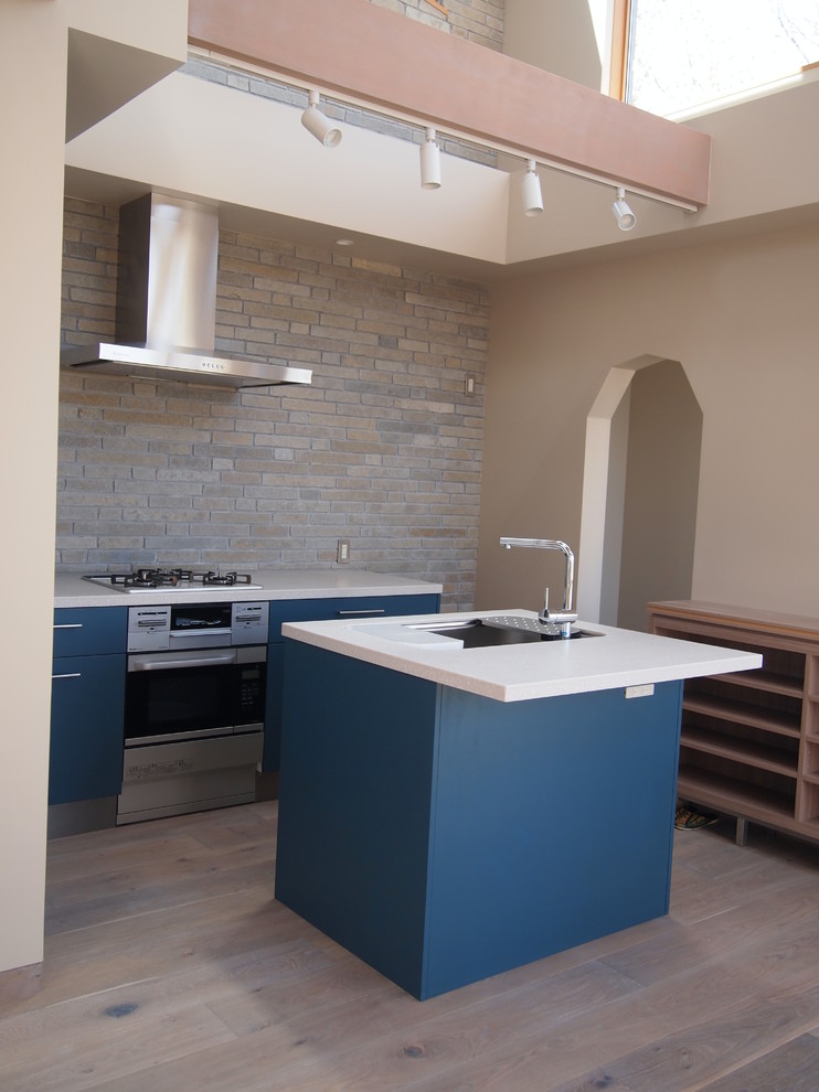 Immagine di una cucina moderna di medie dimensioni con lavello sottopiano, ante lisce, ante in legno chiaro, top in superficie solida, paraspruzzi bianco, elettrodomestici in acciaio inossidabile, pavimento in compensato e 2 o più isole