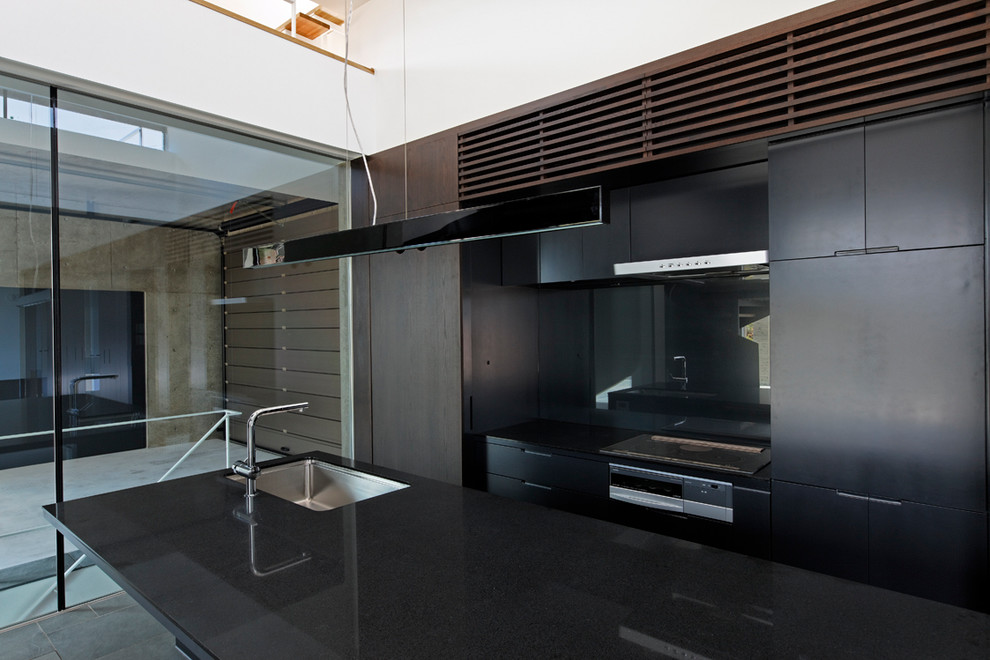 Idées déco pour une cuisine ouverte linéaire de taille moyenne avec des portes de placard noires, une crédence noire, un sol en carrelage de porcelaine, îlot et un sol noir.