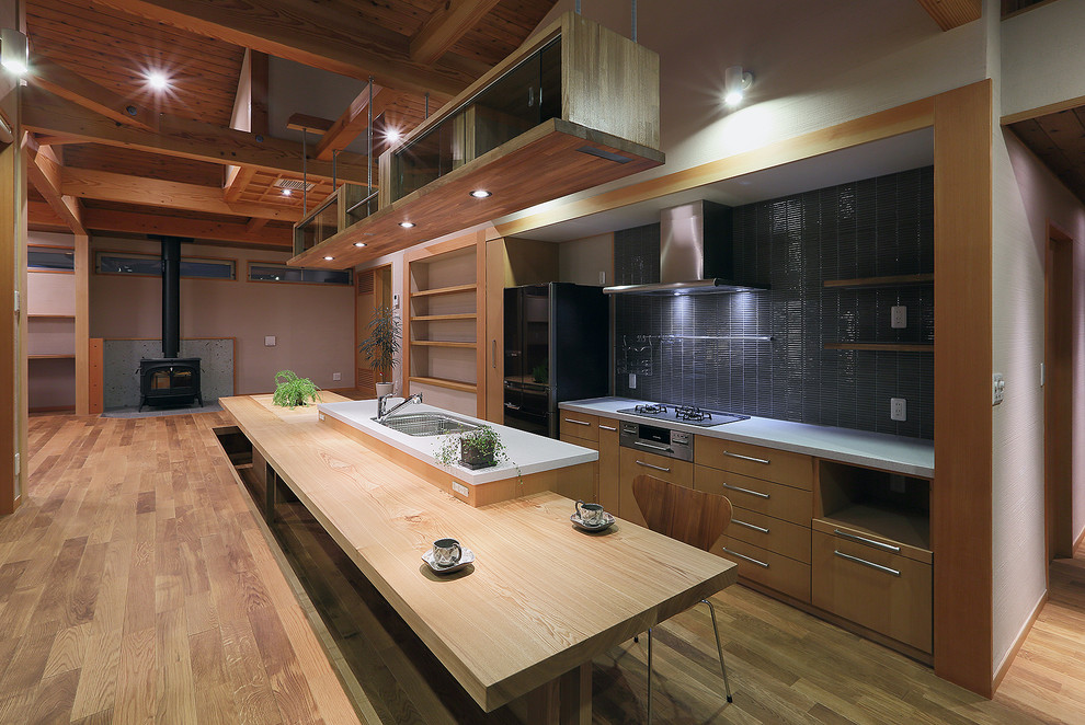 Aménagement d'une cuisine parallèle asiatique en bois clair avec un évier encastré, un placard à porte plane, une crédence grise, un électroménager en acier inoxydable, un sol en bois brun et îlot.