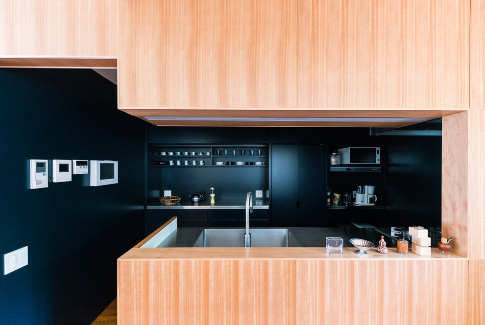 東京23区にあるコンテンポラリースタイルのおしゃれなキッチン (一体型シンク、インセット扉のキャビネット、青いキャビネット、ステンレスカウンター、茶色いキッチンパネル、木材のキッチンパネル、パネルと同色の調理設備、無垢フローリング、アイランドなし、茶色い床) の写真