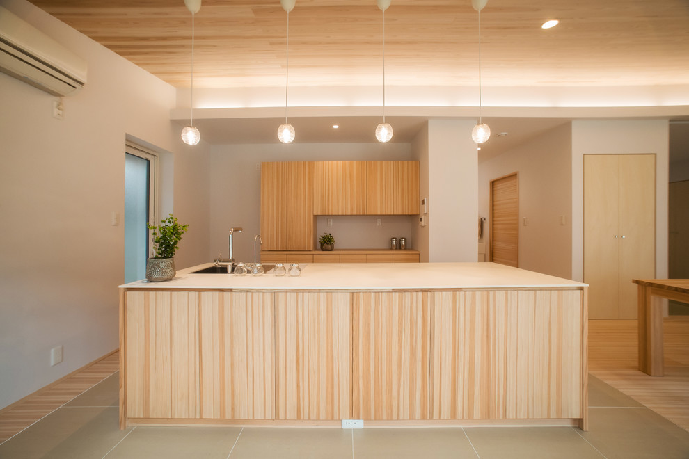 Idée de décoration pour une cuisine ouverte parallèle asiatique en bois brun avec un évier 1 bac, un placard à porte plane, îlot et un sol gris.