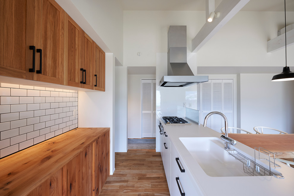 Offene, Zweizeilige Moderne Küche mit hellbraunen Holzschränken, integriertem Waschbecken, flächenbündigen Schrankfronten, Küchengeräten aus Edelstahl und braunem Holzboden in Sonstige