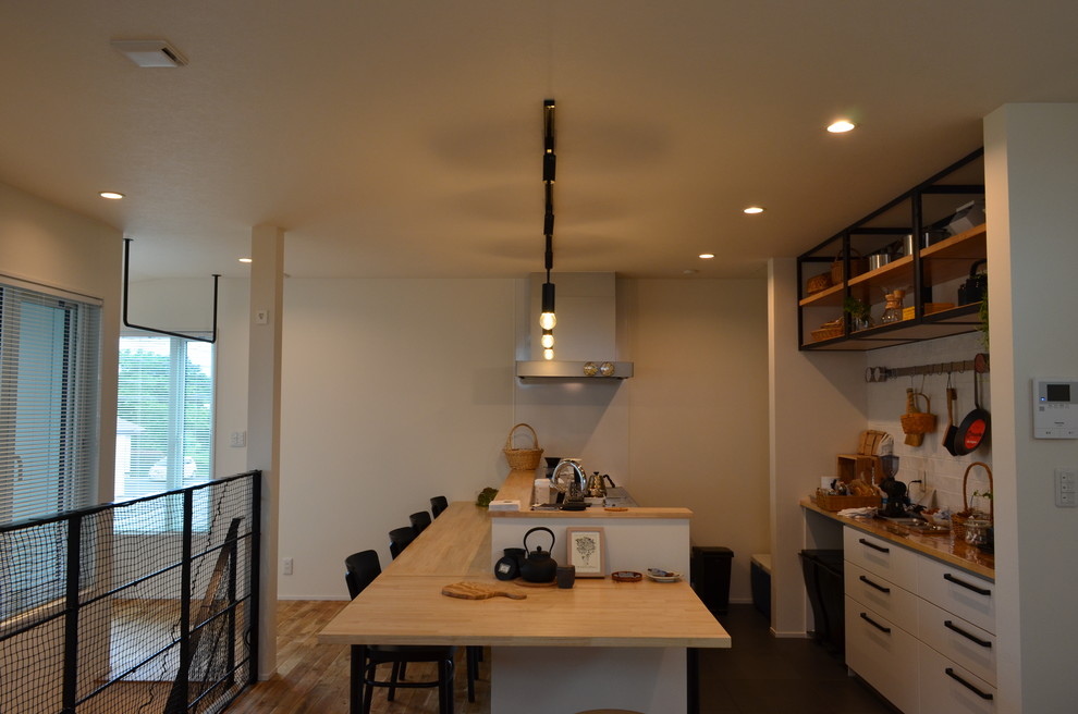 Exempel på ett litet minimalistiskt linjärt kök med öppen planlösning, med en integrerad diskho, luckor med profilerade fronter, vita skåp, bänkskiva i rostfritt stål, vitt stänkskydd, linoleumgolv och svart golv