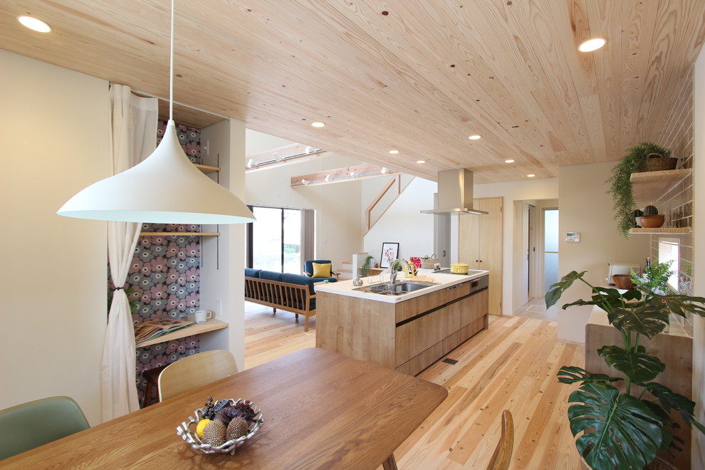 Идея дизайна: кухня-гостиная в восточном стиле с одинарной мойкой, плоскими фасадами, фасадами цвета дерева среднего тона, светлым паркетным полом, островом и бежевым полом