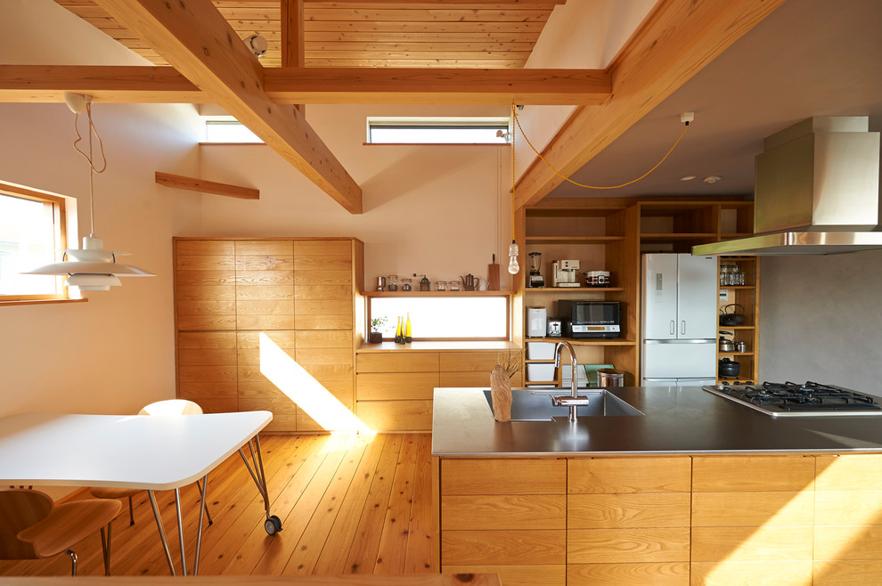 Пример оригинального дизайна: кухня-гостиная в современном стиле с одинарной мойкой, плоскими фасадами, фасадами цвета дерева среднего тона, столешницей из нержавеющей стали и паркетным полом среднего тона