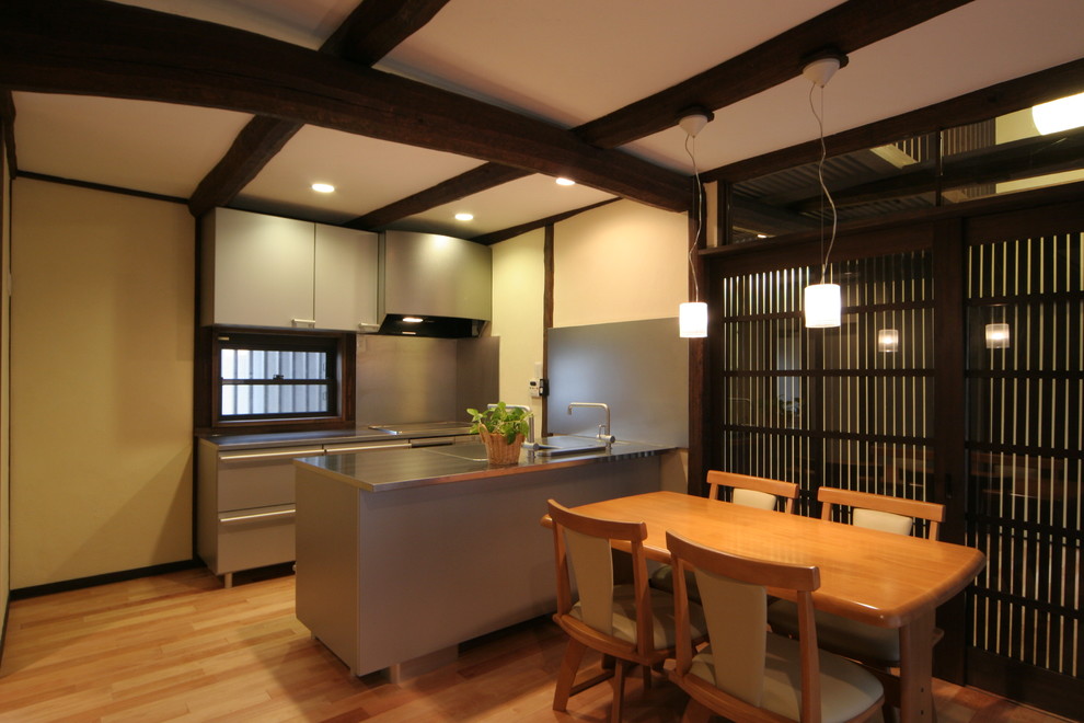 Exempel på ett litet asiatiskt grå grått kök, med en integrerad diskho, skåp i rostfritt stål, bänkskiva i rostfritt stål, stänkskydd med metallisk yta, stänkskydd i trä, rostfria vitvaror, mellanmörkt trägolv, en köksö och beiget golv