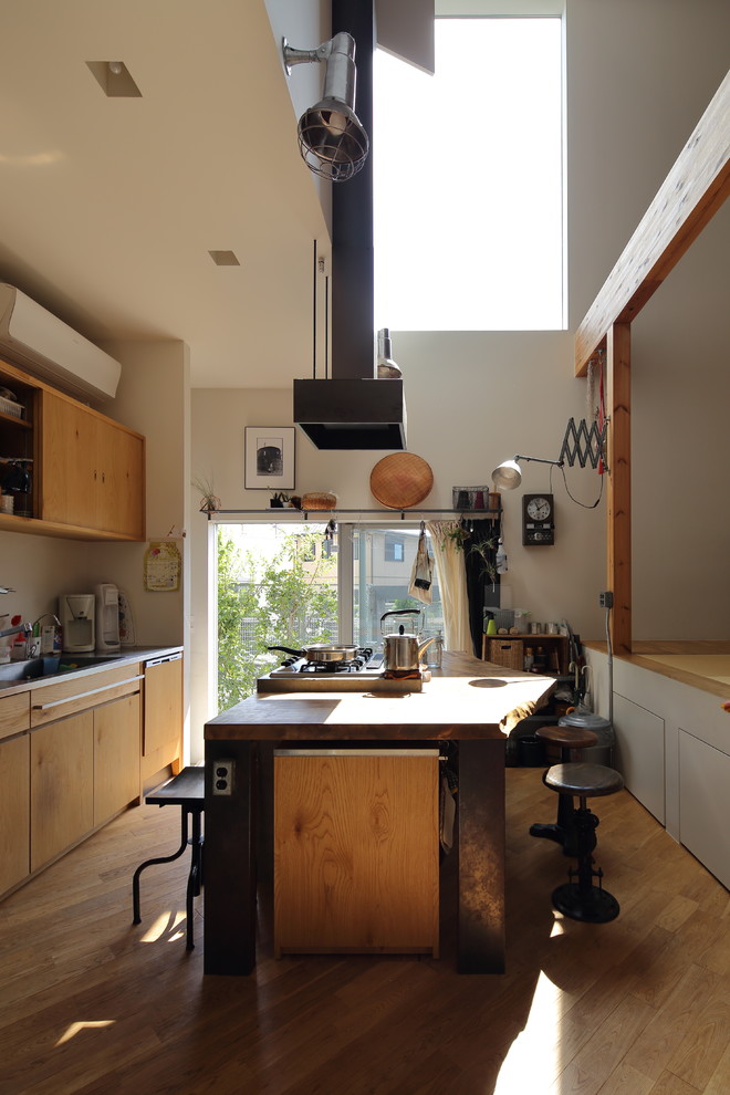 Photo of a world-inspired galley kitchen in Osaka with flat-panel cabinets, medium wood cabinets, medium hardwood flooring, an island and brown floors.