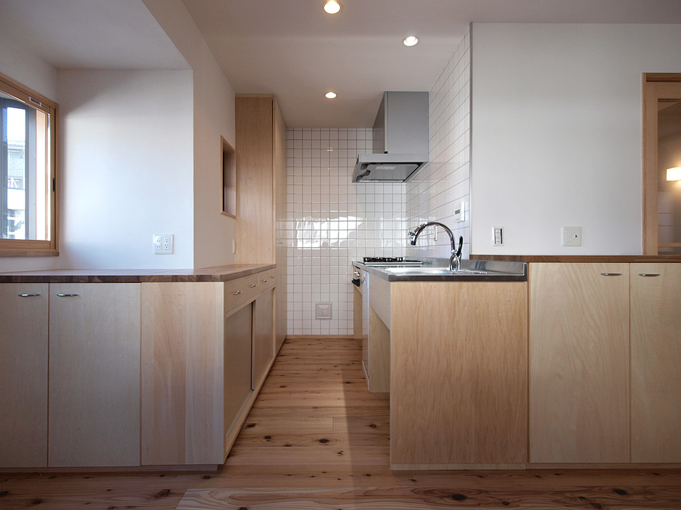 Einzeilige Skandinavische Küche mit Edelstahl-Arbeitsplatte und hellem Holzboden in Tokio