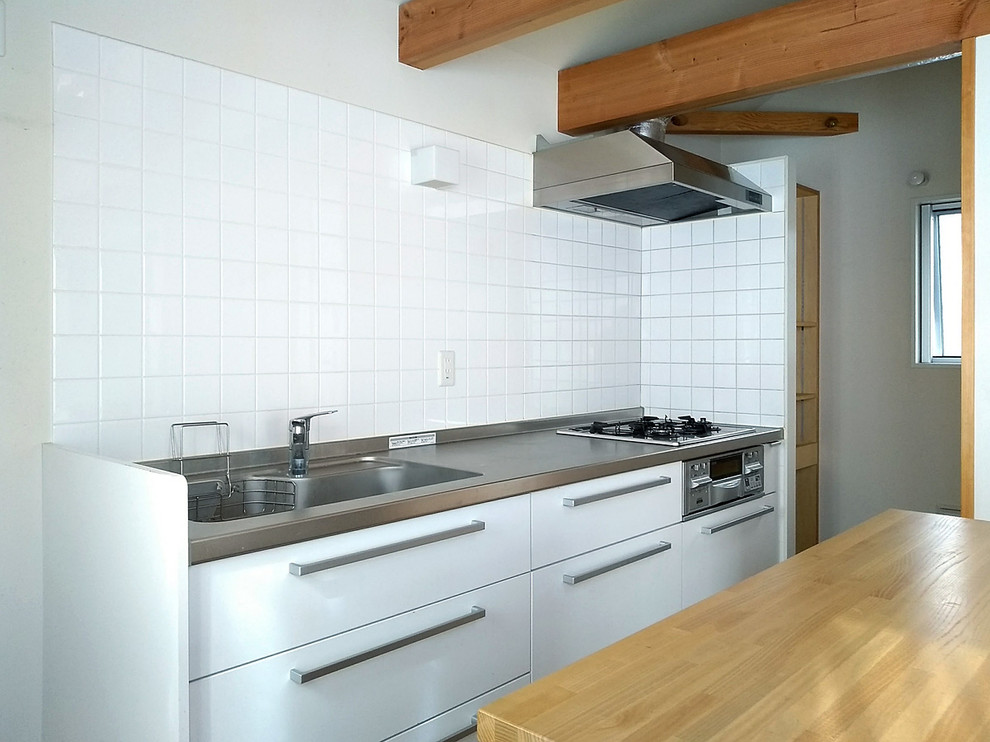 Photo of a scandi single-wall kitchen in Tokyo with stainless steel worktops, white splashback and an island.