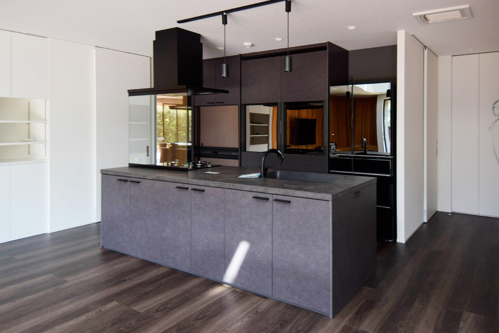 Large trendy galley painted wood floor and brown floor open concept kitchen photo in Other with an undermount sink, black cabinets, black backsplash, paneled appliances, an island and black countertops