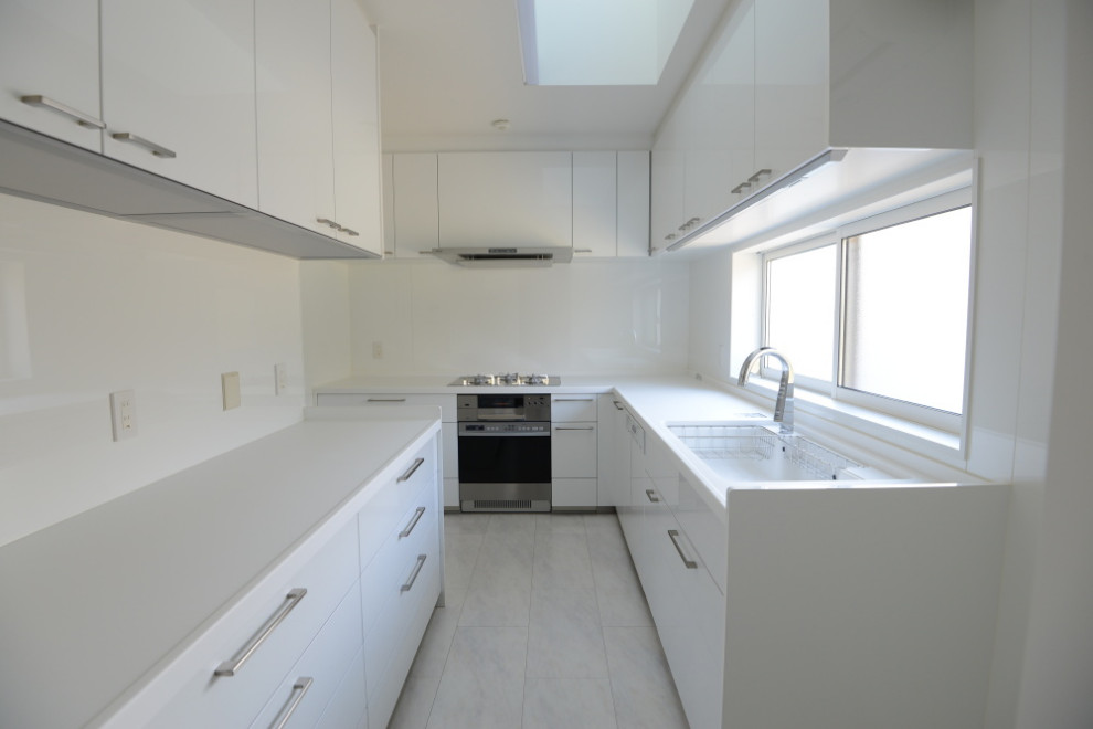 Inredning av ett modernt avskilt, stort vit vitt l-kök, med luckor med profilerade fronter, vita skåp, bänkskiva i koppar, vitt stänkskydd, plywoodgolv och vitt golv