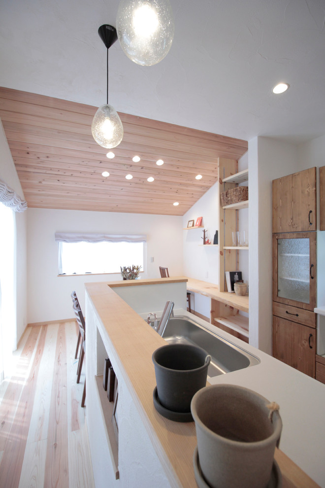 Imagen de cocina comedor lineal de estilo zen con suelo de madera clara y suelo beige