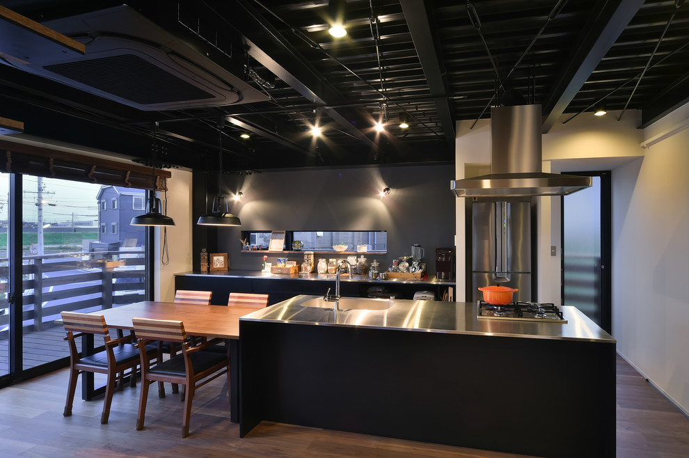 Offene, Zweizeilige Industrial Küche mit Edelstahl-Arbeitsplatte, flächenbündigen Schrankfronten, dunklen Holzschränken, braunem Holzboden, Kücheninsel und braunem Boden in Nagoya
