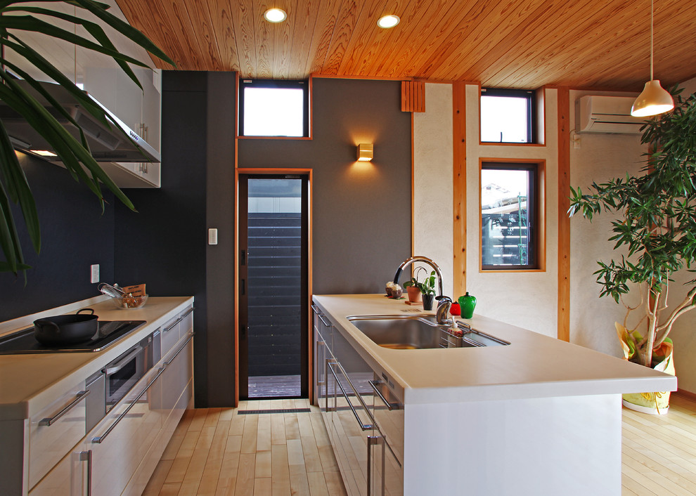 На фото: параллельная кухня в восточном стиле с врезной мойкой, плоскими фасадами, полуостровом, белыми фасадами, белым фартуком, белой техникой и светлым паркетным полом