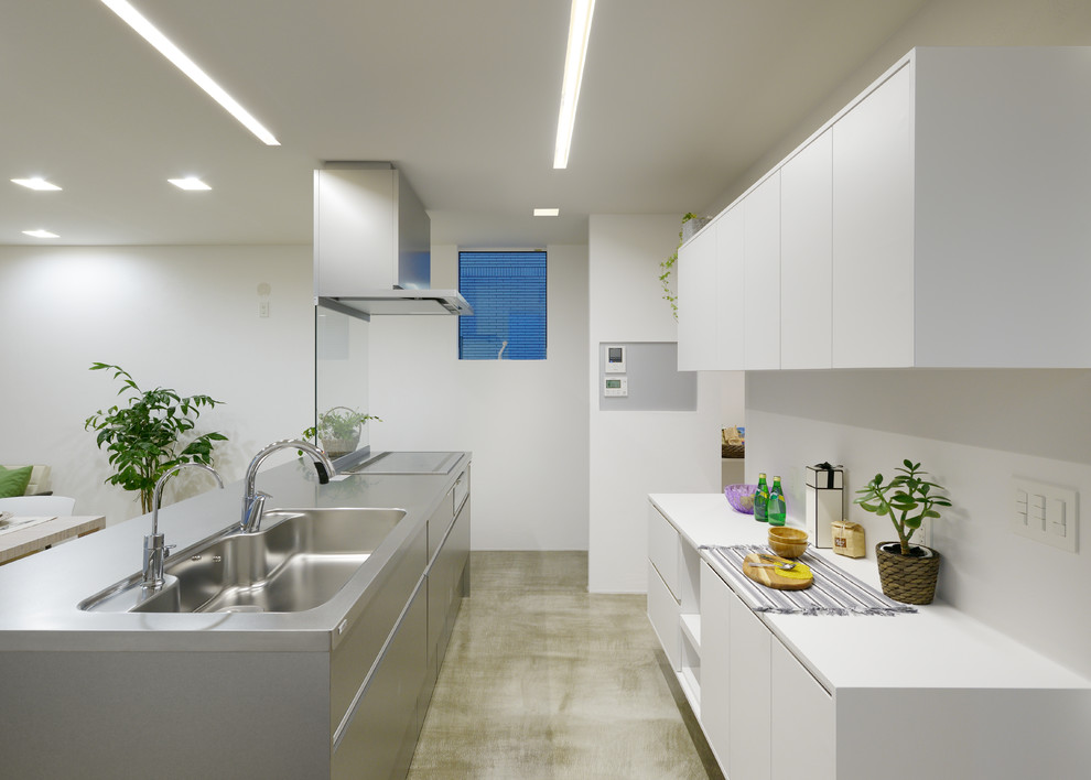 Идея дизайна: параллельная кухня-гостиная в современном стиле с одинарной мойкой, плоскими фасадами, фасадами из нержавеющей стали, столешницей из нержавеющей стали, бетонным полом, островом и серым полом
