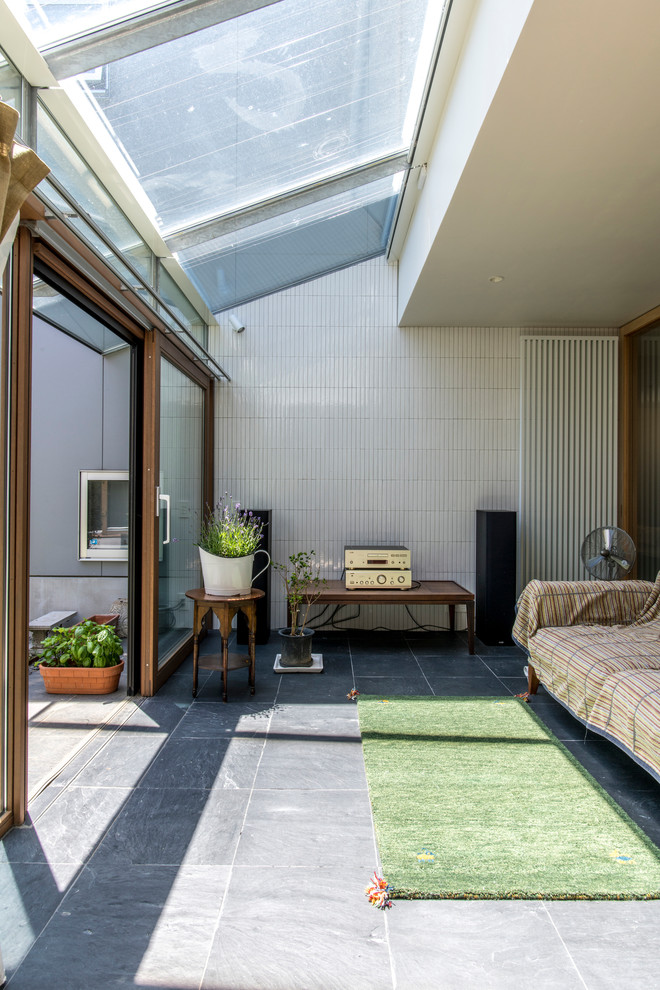 На фото: терраса в современном стиле с полом из керамогранита, стеклянным потолком и черным полом