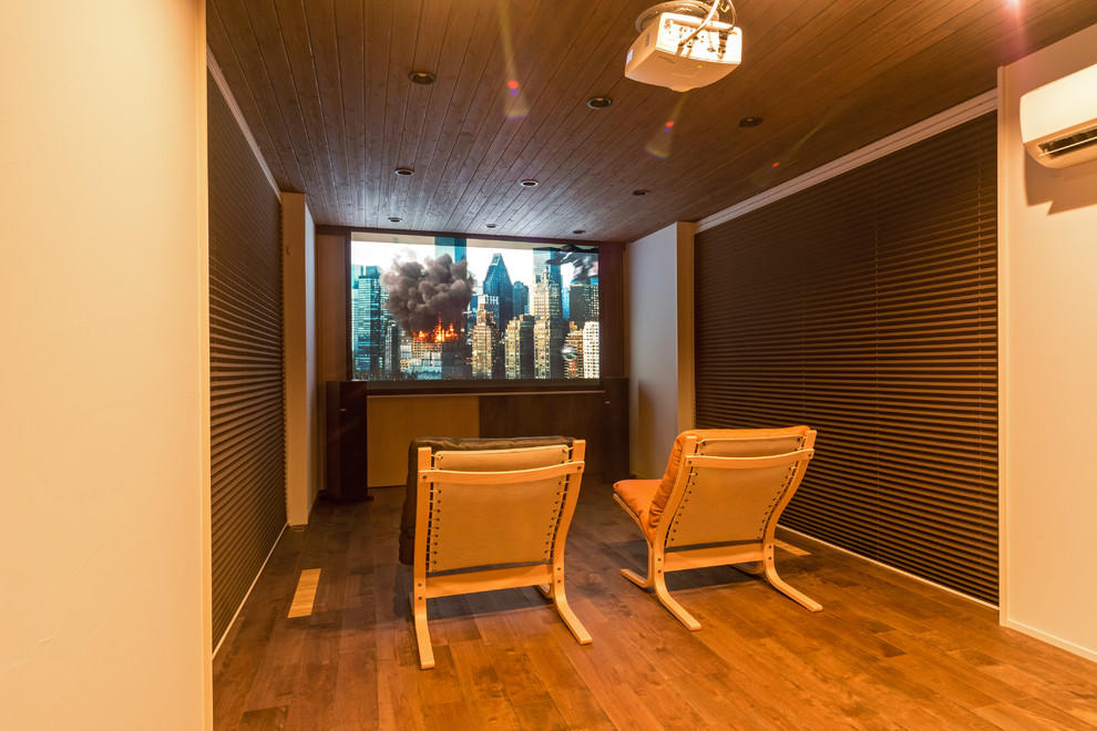 Immagine di un piccolo home theatre etnico chiuso con pareti bianche, pavimento in legno massello medio e pavimento marrone