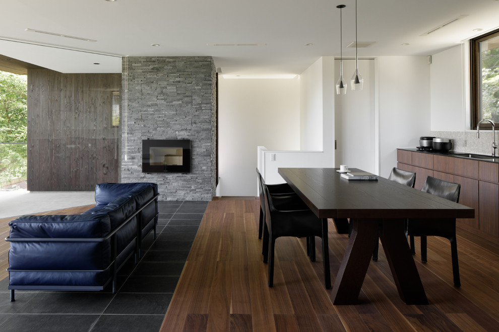 他の地域にあるコンテンポラリースタイルのおしゃれなLDK (白い壁、濃色無垢フローリング、標準型暖炉、石材の暖炉まわり、茶色い床) の写真