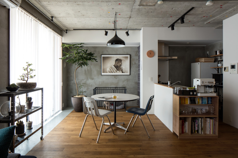 Imagen de comedor industrial abierto con paredes grises, suelo de madera en tonos medios y suelo marrón