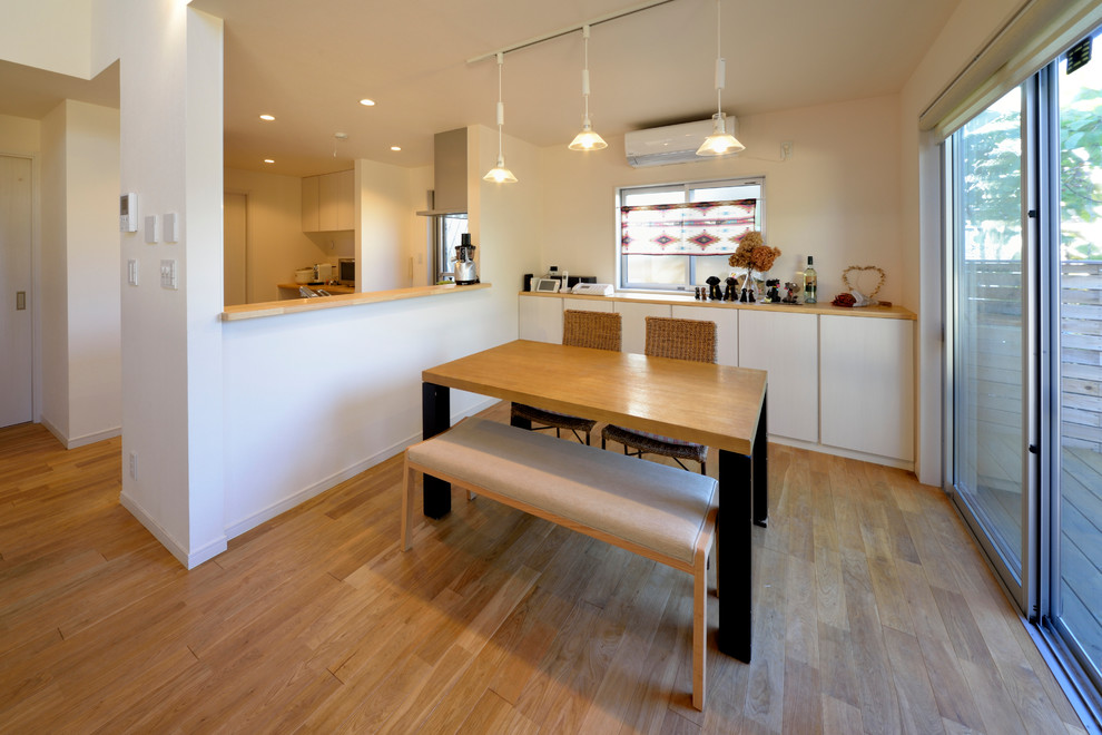 Aménagement d'une salle à manger contemporaine avec un mur blanc et un sol marron.