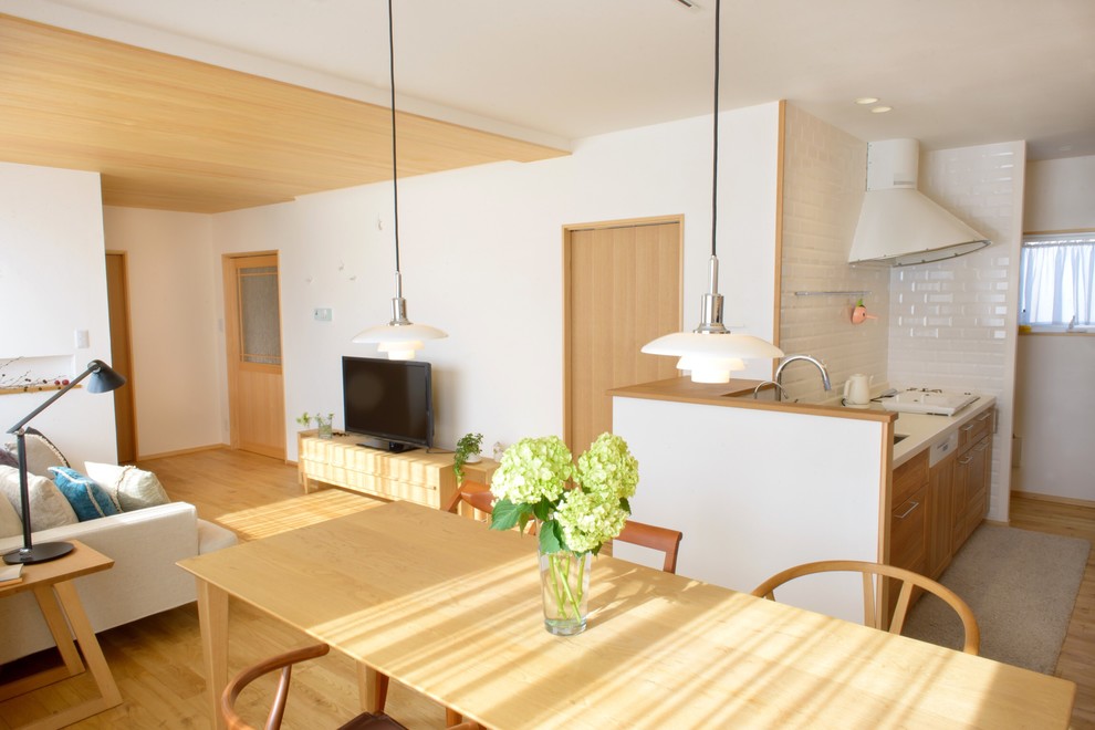 Ispirazione per una sala da pranzo aperta verso il soggiorno scandinava di medie dimensioni con pareti bianche, pavimento in legno massello medio e nessun camino