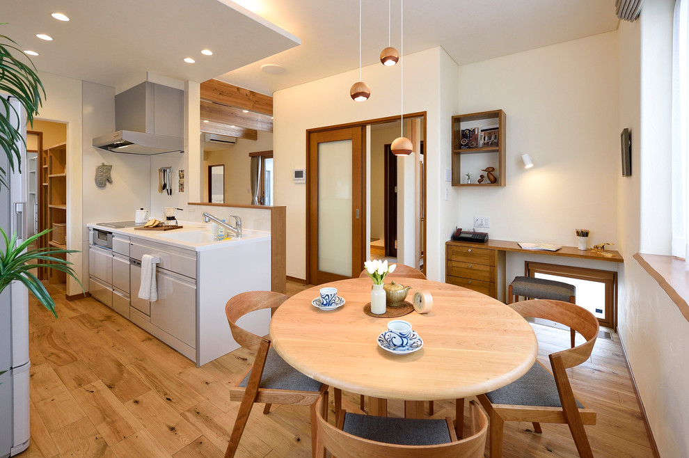 Cette image montre une salle à manger ouverte sur le salon asiatique de taille moyenne avec un mur blanc, un sol en bois brun, aucune cheminée et un sol marron.