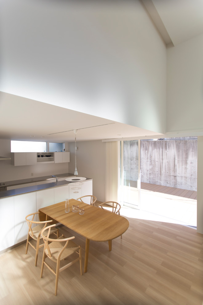 Idéer för en stor minimalistisk matplats med öppen planlösning, med vita väggar och ljust trägolv